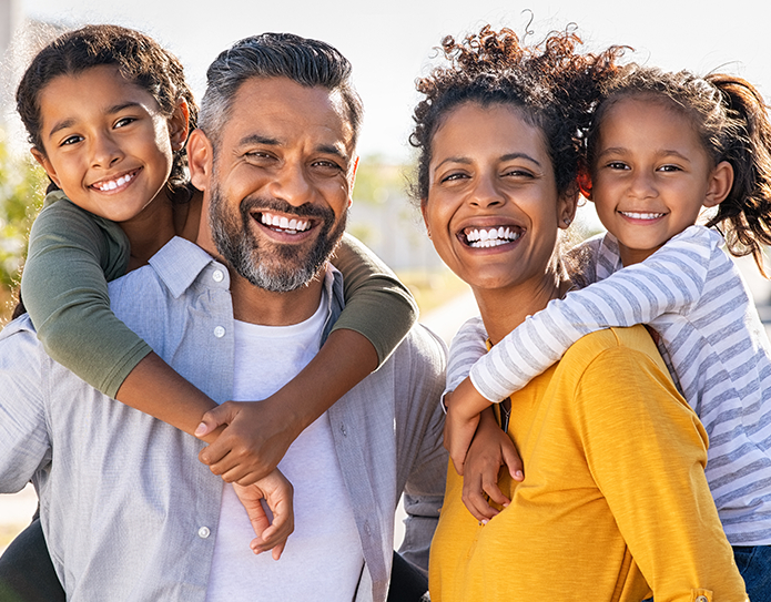 family is smiling and playing outside 